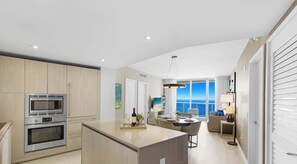 Uma cozinha moderna com eletrodomésticos embutidos, uma ilha central e vista para o oceano.
