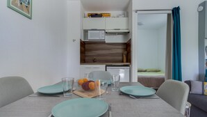A compact living space with a dining area, kitchenette, and a shower. - Le Loriot - One Bedroom Apartment, Sleeps 4 (Saint-Nic)