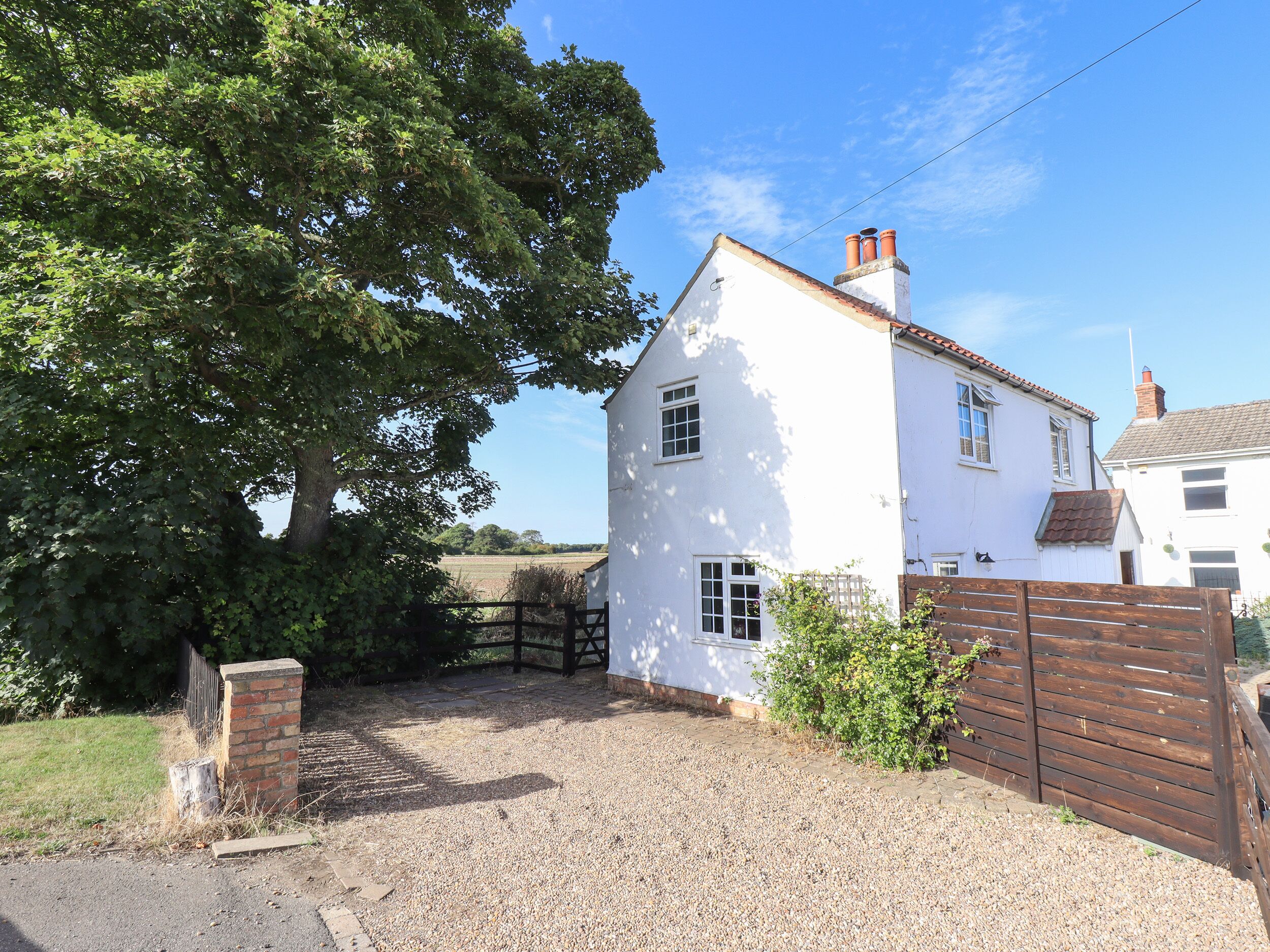 A white house with a gravel driveway and a wooden gate.