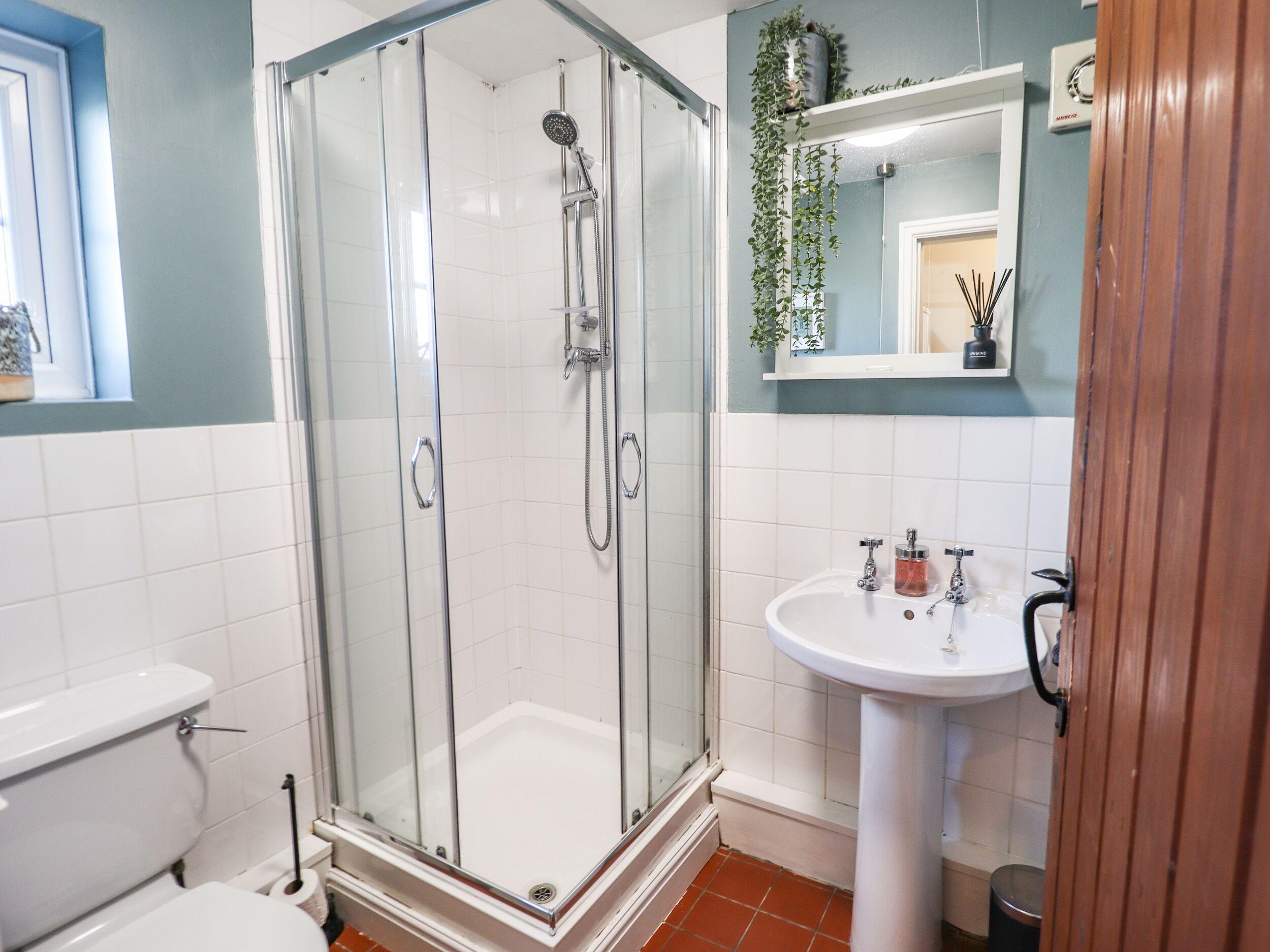 A bathroom with a glass-enclosed shower, a white sink, and a toilet.