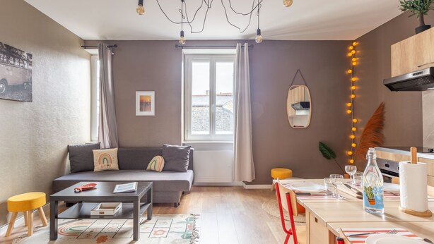 A modern living room with a sofa, coffee table, and dining area with a table set for two.
