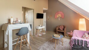 A cozy room with a dining table, a TV, a fan, and a sofa. - Varde - appartement avec jardin (Saint-Coulomb)