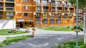 Een meerlaags houten gebouw met balkons, een overdekte ingang en terras.
