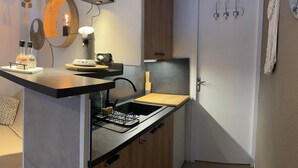 Een compacte keuken met een ingebouwd spoelbakje, houten kastjes, een klein aanrecht en een spiegel aan de muur.