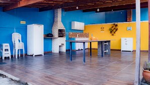 An outdoor patio with a brick oven, white refrigerator, and a table with chairs. - Ribeiro Lugar de Paz Casa 1 (Arraial do Cabo)