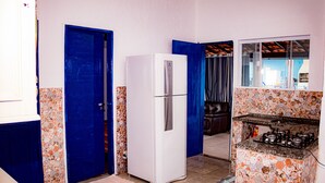 A compact kitchen with a white refrigerator, a patterned backsplash, and a gas stove. - Ribeiro Lugar de Paz Casa 1 (Arraial do Cabo)
