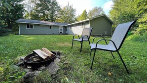 Ein Garten mit Feuerstelle, zwei Stühlen und einem Haus im Hintergrund.