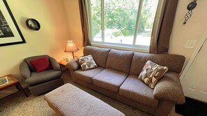 Ein Wohnzimmer mit einer Couch, einem Sessel, einem Couchtisch und einer Lampe.