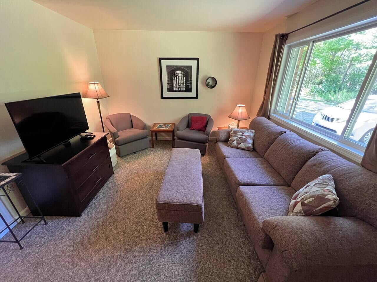 A living room with a television, two sofas, a coffee table, and a window with a view.