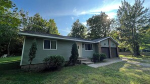 Ein eingeschossiges Haus mit Veranda, Garage und gepflegtem Rasen.