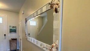 Un couloir avec un grand miroir, un plancher en bois et un petit tapis.