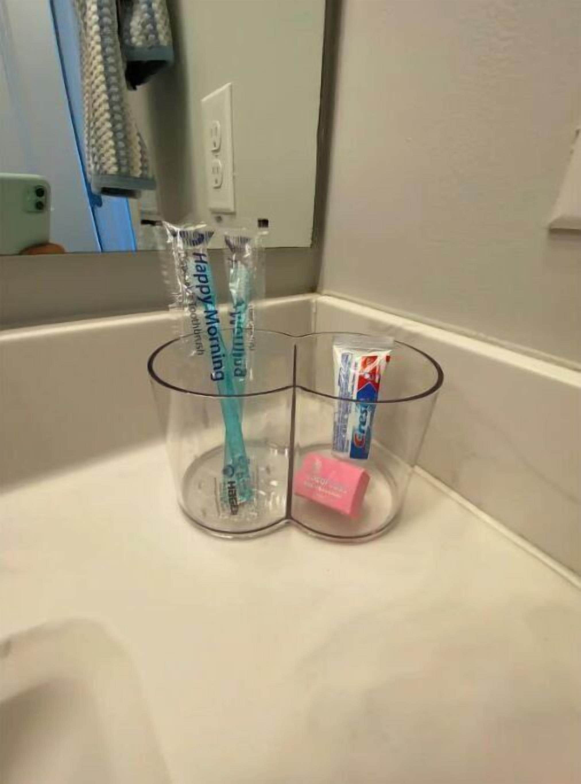 Ein Waschbecken mit einer transparenten Seifenspender aus Glas und einer rosa Seife.