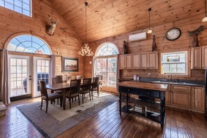 A spacious log cabin with a dining area, kitchen, and large windows.