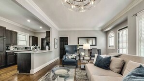 A spacious living room with a sofa, a coffee table, and a dining area with a kitchen in the background. - Welcome to your Dallas escape — a luxurious 1-bedroom, 1-bath condo nestled in the prestigious Swiss Ave district. Perfect for 2 guests, this retreat blends timeless elegance with modern amenities for an unforgettable stay. (Dallas)
