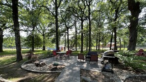 Un patio al aire libre con suelo de piedra, una parrilla y varias sillas.