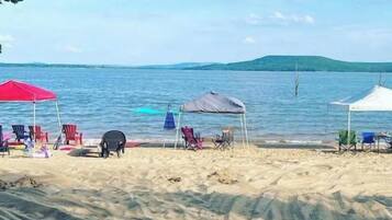 A beach with several umbrellas and chairs, a tent, and a calm sea.