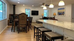 Una cocina moderna con una isla central, sillas de madera, una mesa de comedor y una estufa empotrada.