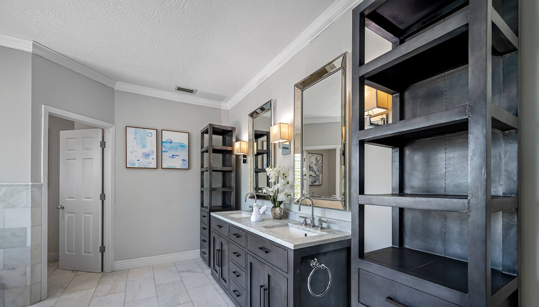 Une salle de bain moderne avec un grand miroir, des meubles de couleur sombre et un comptoir en marbre.