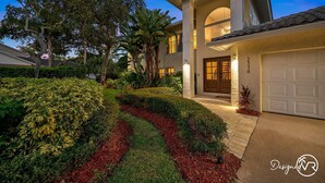 A modern two-story house with a well-maintained garden, a garage, and a large tree in the front yard. - 8BR Villa with Heated Pool Near Beach (Largo)