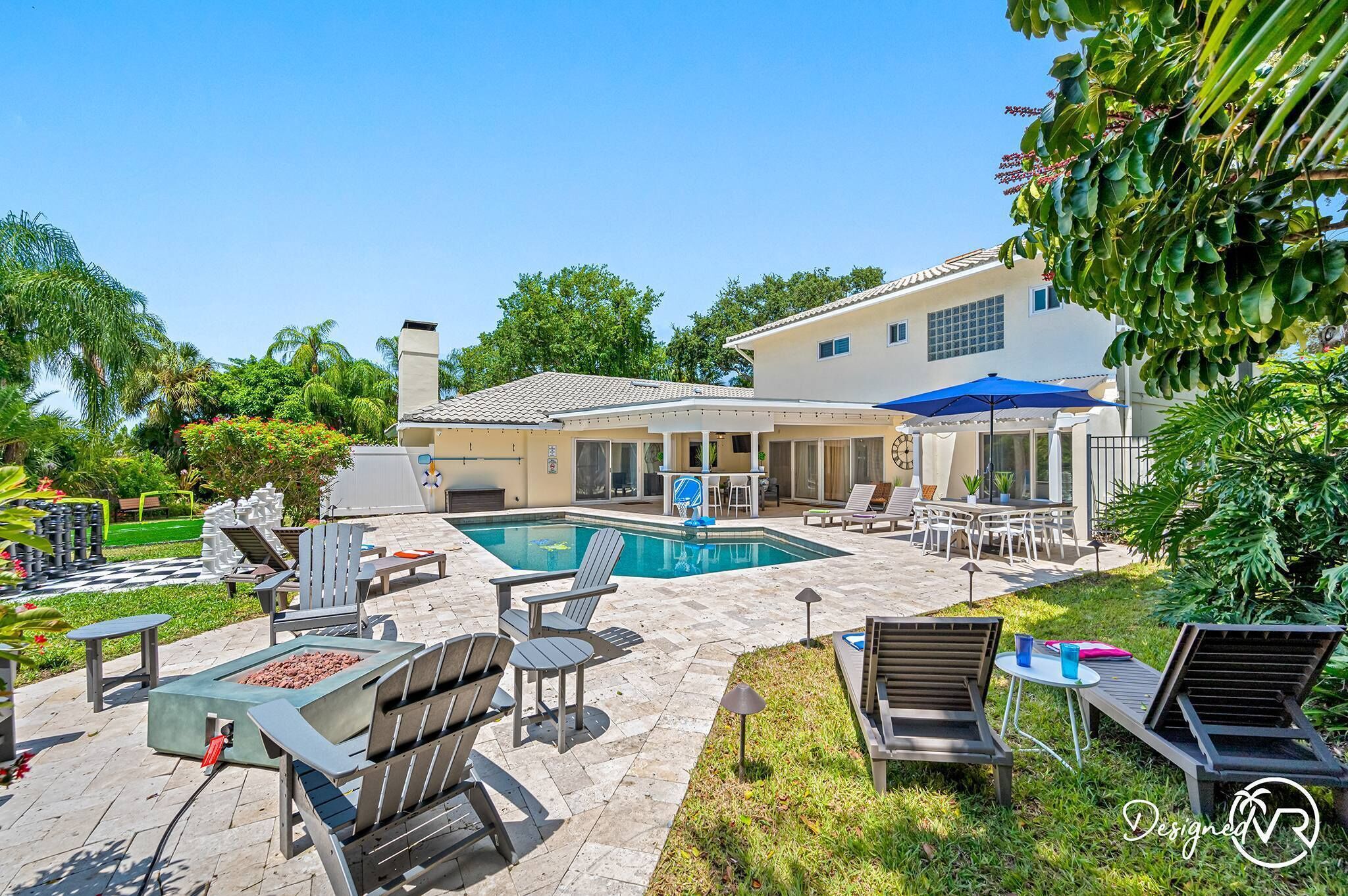A backyard with a swimming pool, outdoor seating, and a patio area.