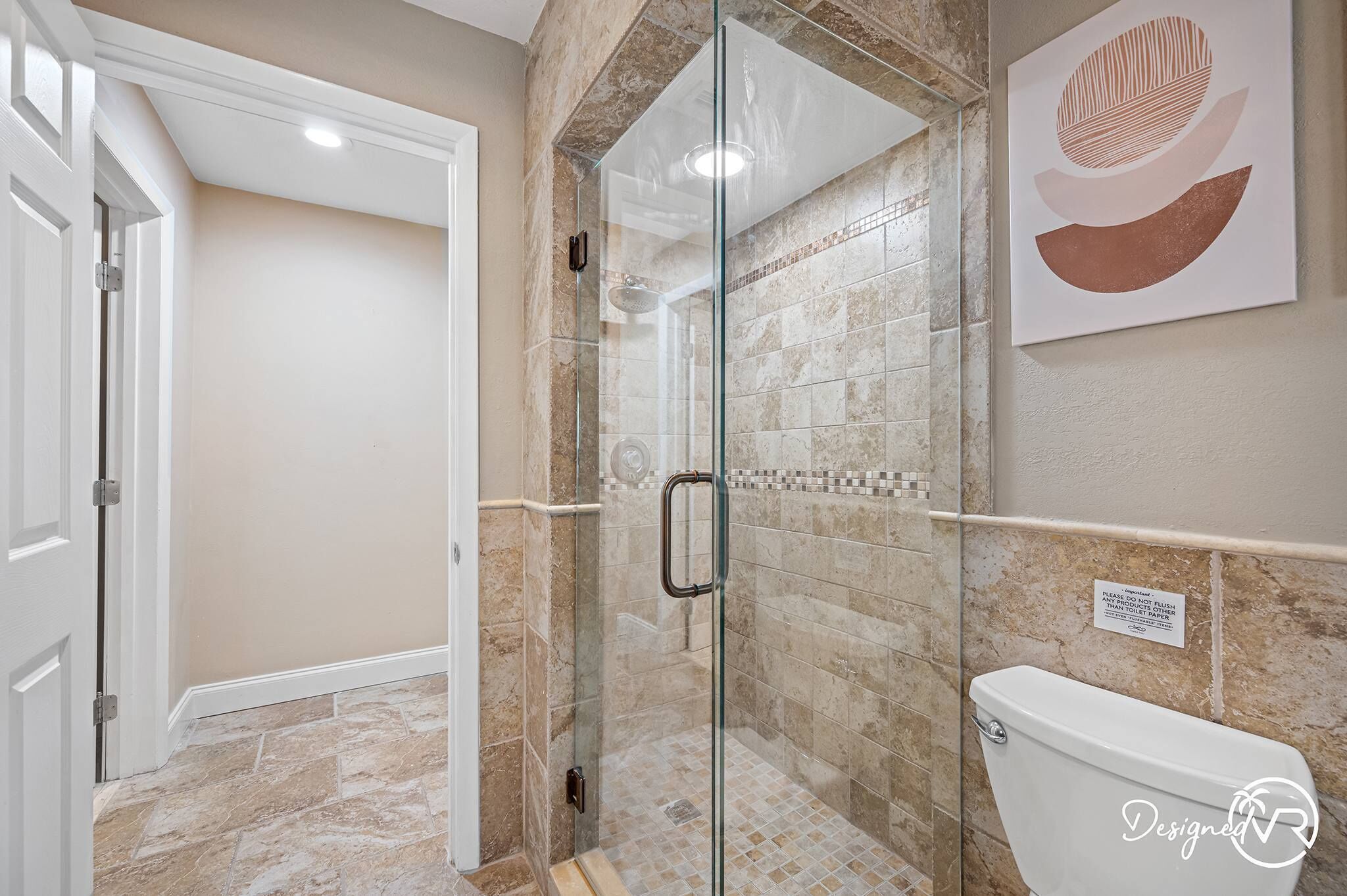 A modern bathroom with a glass-enclosed shower, a toilet, and a tiled floor.