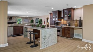 A modern kitchen with a central island, dark wooden cabinets, and a herringbone-patterned backsplash. - 8BR Villa with Heated Pool Near Beach (Largo)
