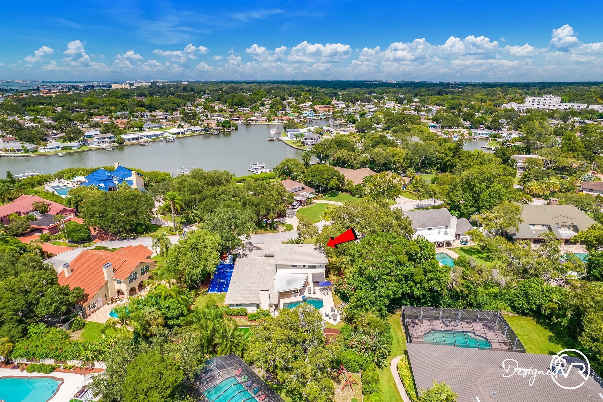 Vue aérienne d’un quartier résidentiel avec des maisons, un lac et une piscine.