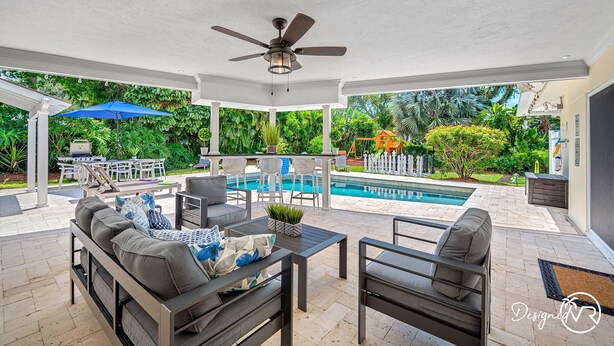 An outdoor patio with a pool, seating area, and ceiling fan. - 8BR Villa with Heated Pool Near Beach (Largo)