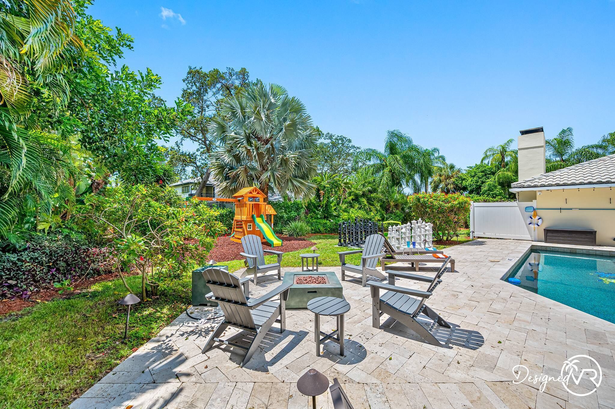Un patio al aire libre con sillas Adirondack, un brasero y una piscina.