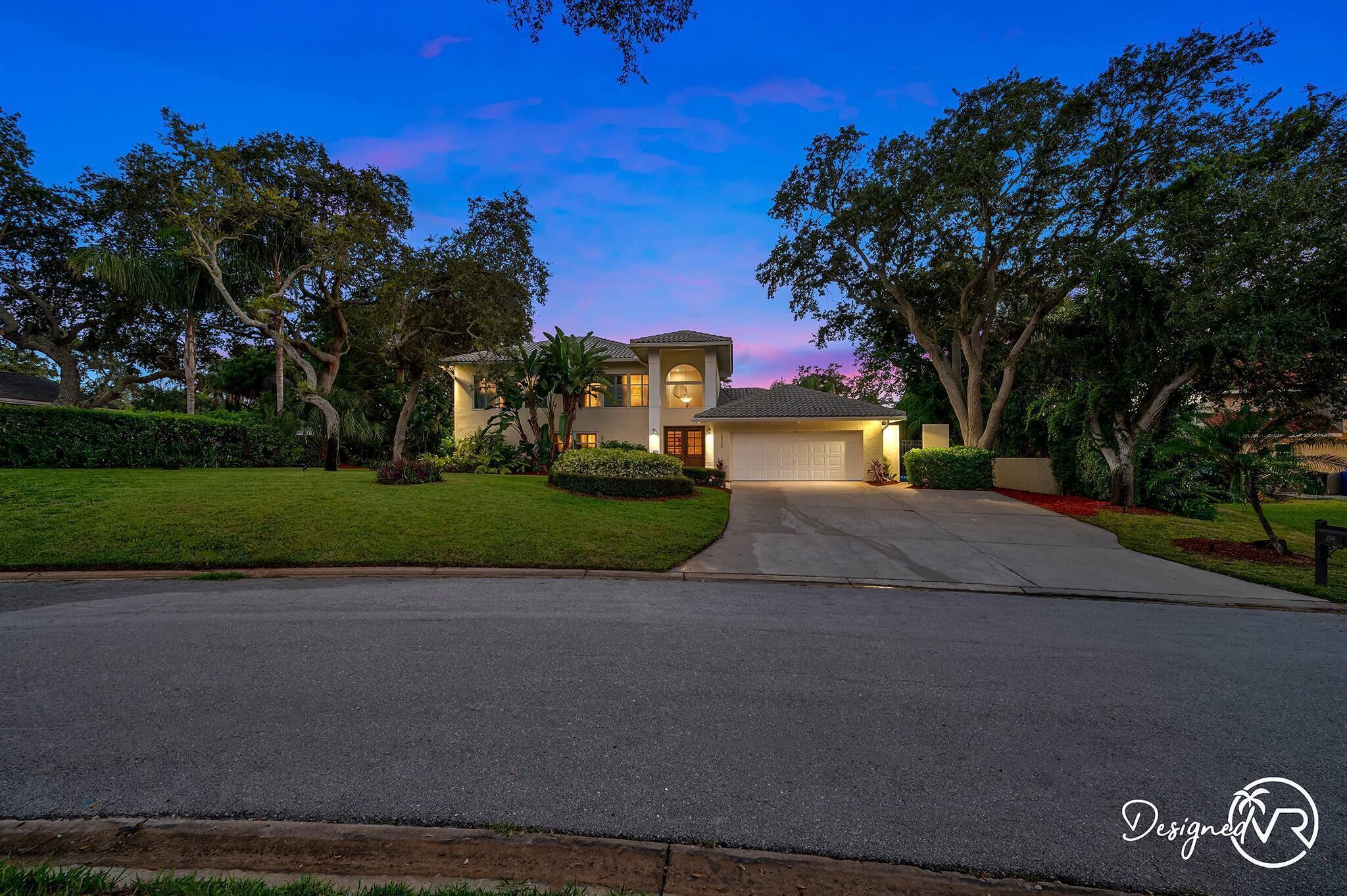 A two-story house with a garage, surrounded by well-maintained lawns and trees.
