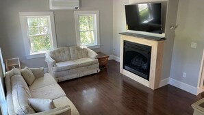 Una sala de estar con chimenea, sofá y televisión.