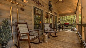 A wooden cabin with a porch featuring rocking chairs, a small table, and a potted plant. - Relaxing Getaway! Cozy Log Cabin, Hot Tub + Firepit (Cherry Log)