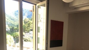 A hotel room with a large window, a bed with white towels, an orange chair, and a red and black artwork on the wall. - Camogli Eden Luxury - spacious and cozy apartment by the sea (Camogli)
