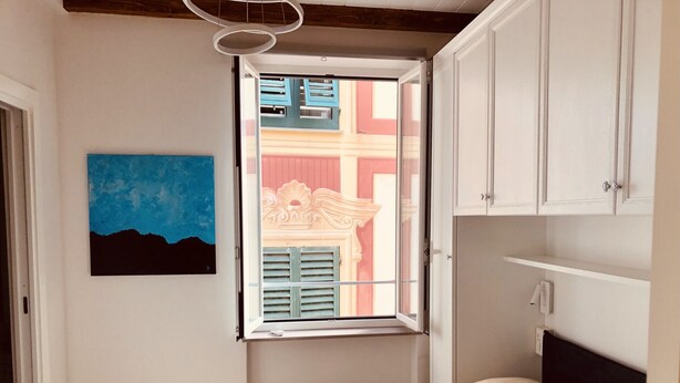 A bedroom with a bed, a window with shutters, a painting, and a white wardrobe. - Camogli Eden Luxury - spacious and cozy apartment by the sea (Camogli)