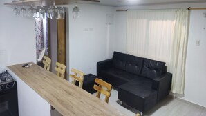 A modern kitchen with a wooden countertop, a black leather sofa, and a dining area with wooden chairs. - San San Andrés Magic House 0 by BBBSAI (San Andrés)