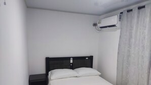 A small, neatly made room with a single bed, a bedside table, and an air conditioning unit mounted on the wall. - San San Andrés Magic House 0 by BBBSAI (San Andrés)