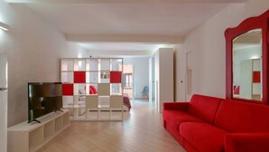 Un salon moderne avec un téléviseur à écran plat, un canapé rouge et un meuble de rangement blanc.