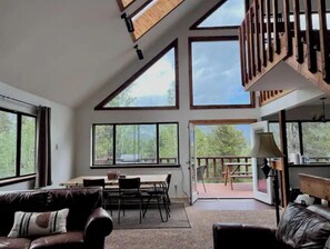 A spacious living area with large windows, a dining table, and a leather sofa. - Window of the Rockies! (Bailey)