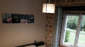 A bedroom with a bed, a nightstand, a window with curtains, and a wall-mounted lamp.