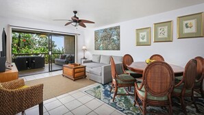 A spacious living area with a dining table, chairs, a sofa, and a ceiling fan. - NEW! Quiet Ocean-view 1st floor | Patio | Pool (Kailua Kona)