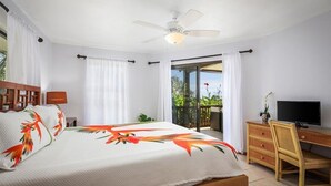 A bedroom with a bed, a desk, a television, and a balcony with a view of greenery. - NEW! Quiet Ocean-view 1st floor | Patio | Pool (Kailua Kona)