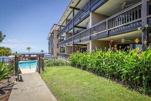 Um hotel com piscina, várias varandas e vista para o mar.