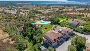 Vista aérea de una propiedad costera con piscina, varias construcciones y follaje circundante.