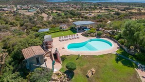 Vista aérea de una propiedad con piscina, un porche cubierto y vistas del paisaje circundante.