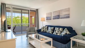 Ein Wohnzimmer mit einer Couch, einem Glastisch, einer Lampe und einem Deckenventilator.