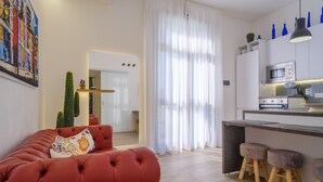 A modern living room with a red sofa, a kitchen area with a microwave and oven, and a large window with sheer curtains. - Holiday Apartment Fico D'India with Sea View, Terrace & Wi-Fi (San Cataldo)