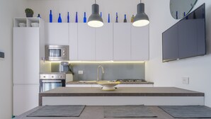 A modern kitchen with a central island, built-in appliances, and pendant lighting. - Holiday Apartment Fico D'India with Sea View, Terrace & Wi-Fi (San Cataldo)