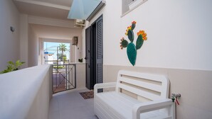 A white bed in a narrow hallway with a glass door leading to a balcony. - Holiday Apartment Fico D'India with Sea View, Terrace & Wi-Fi (San Cataldo)