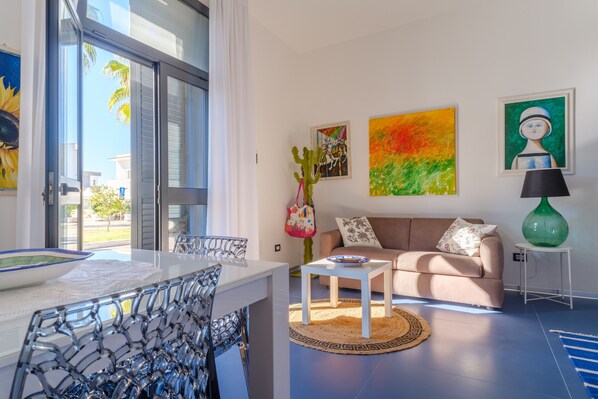 A modern living room with a sofa, coffee table, and artwork on the walls.