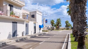Una calle con un edificio que tiene balcones, un toldo azul y un cielo despejado.